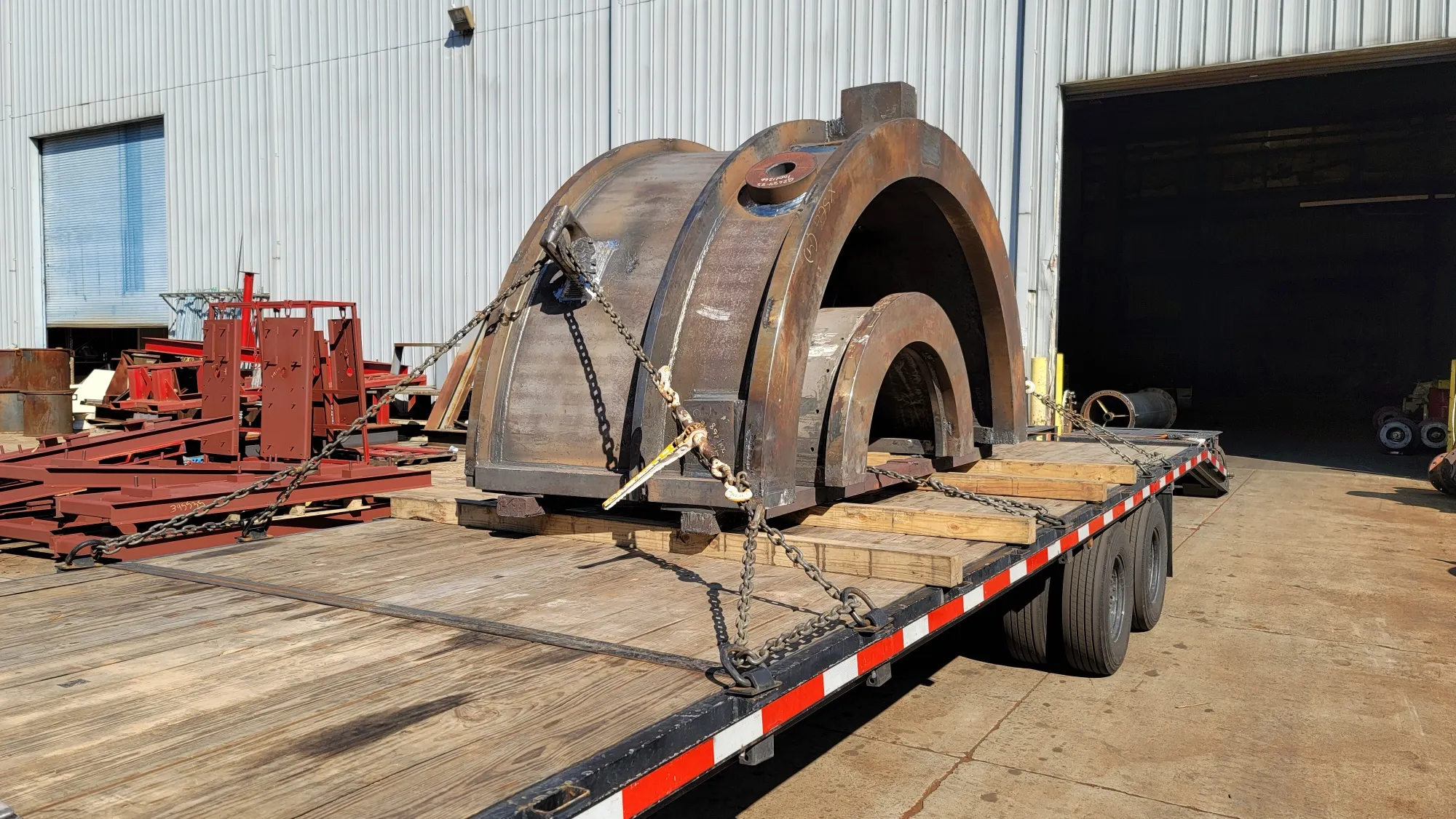 Heavy machined steel components — 'big iron' — chained on a flatbed